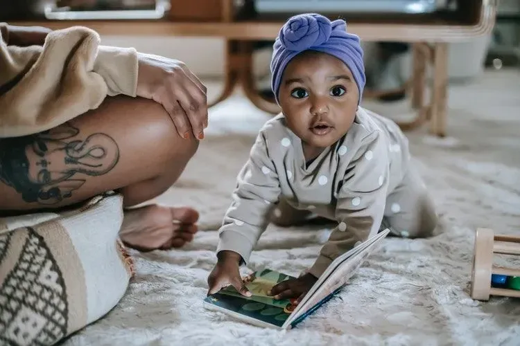A cute baby girl crawling with a book