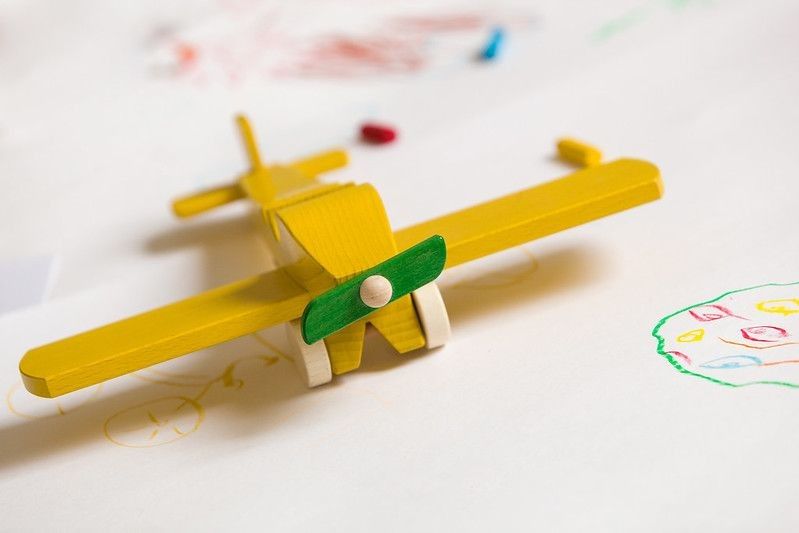 Yellow wooden toy plane on the white background.