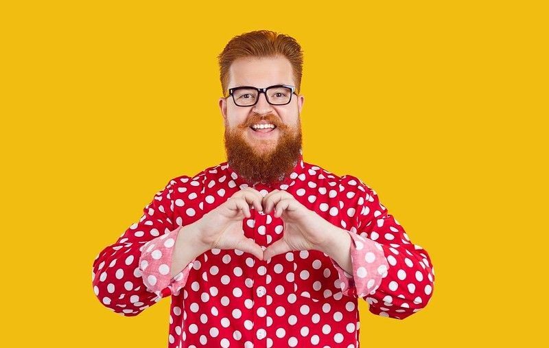 Cheerful plus size man making love sign with hands.