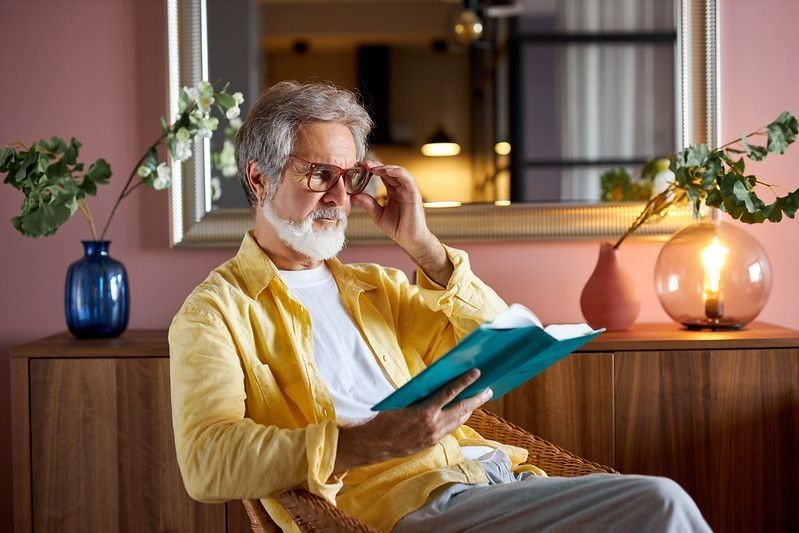 An old man reading a book while wearing bifocal glasses