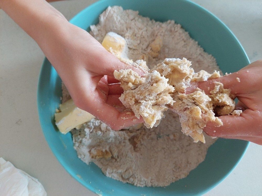Rubbing butter with flour to create a crumble to make the cookie biscuit dough.