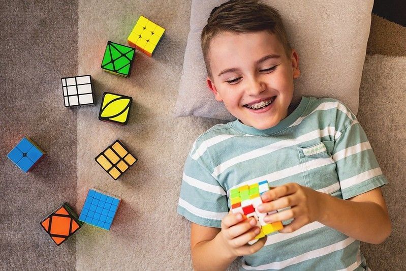 Young boy assembling multicolored Rubiks cube