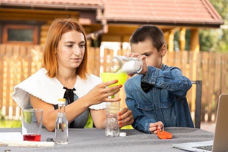 Mom and son creating a rocket launcher using a bottle, soda and vinegar.