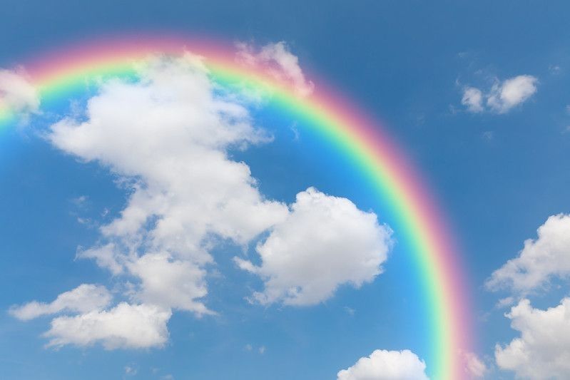 Rainbow and clouds in sky background.