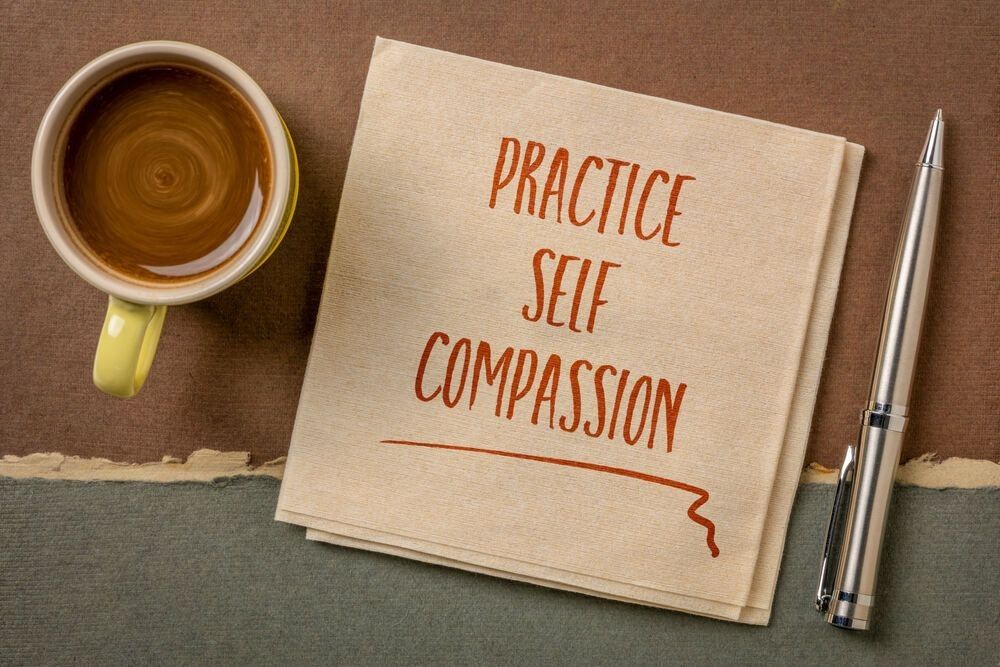 practice self-compassion inspirational handwriting on a napkin with coffee,