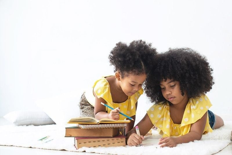 Two ethnic sisters studying together.