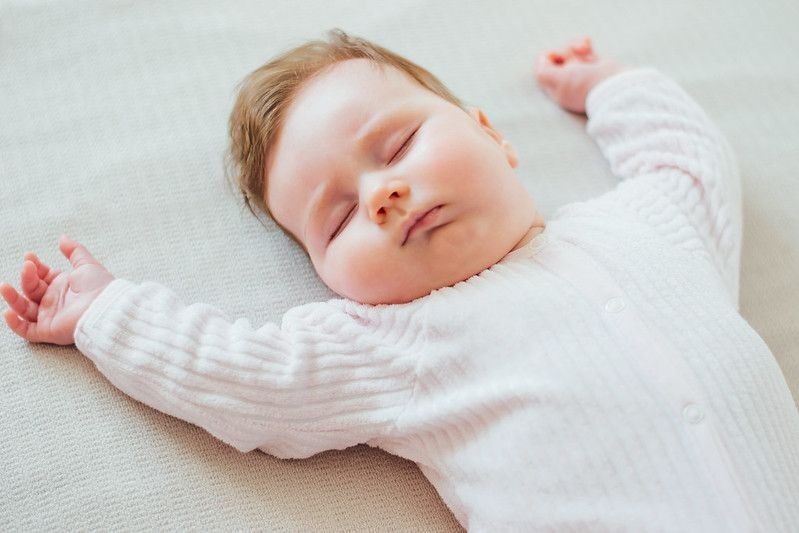 Infant baby sleeping on white sheets