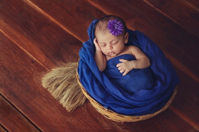 Newborn baby wrapped in blue blanket sleeping in a basket