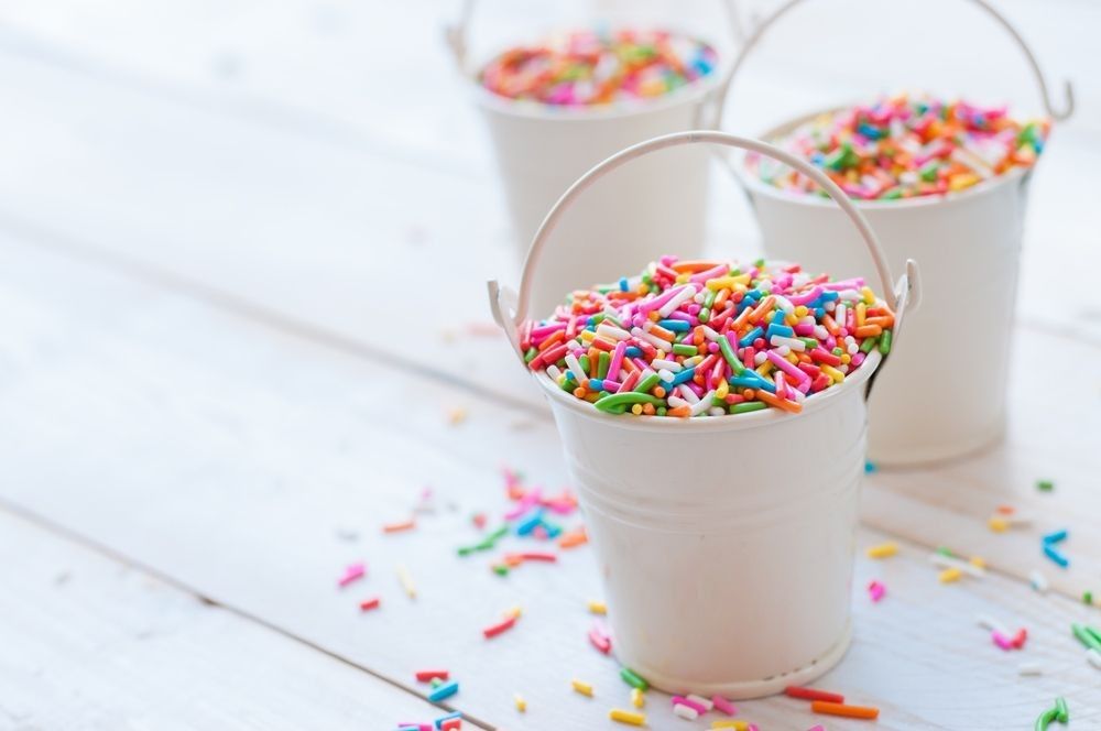 A lot of sprinkles in a bucket on white wooden board background