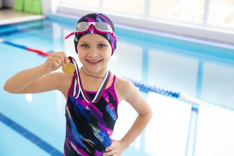 Portrait of little swimmer with medal in hand.