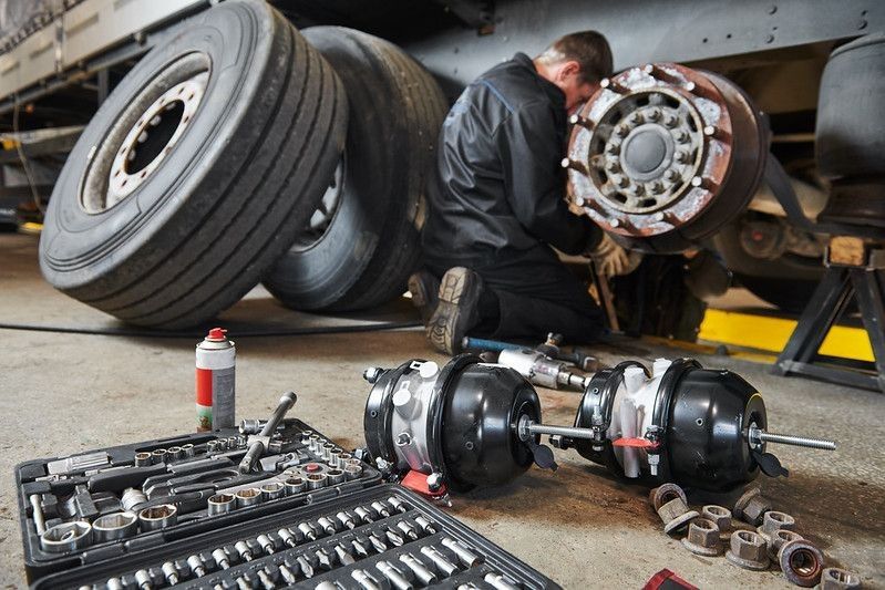Truck repairing service- mechanic works on brakes.