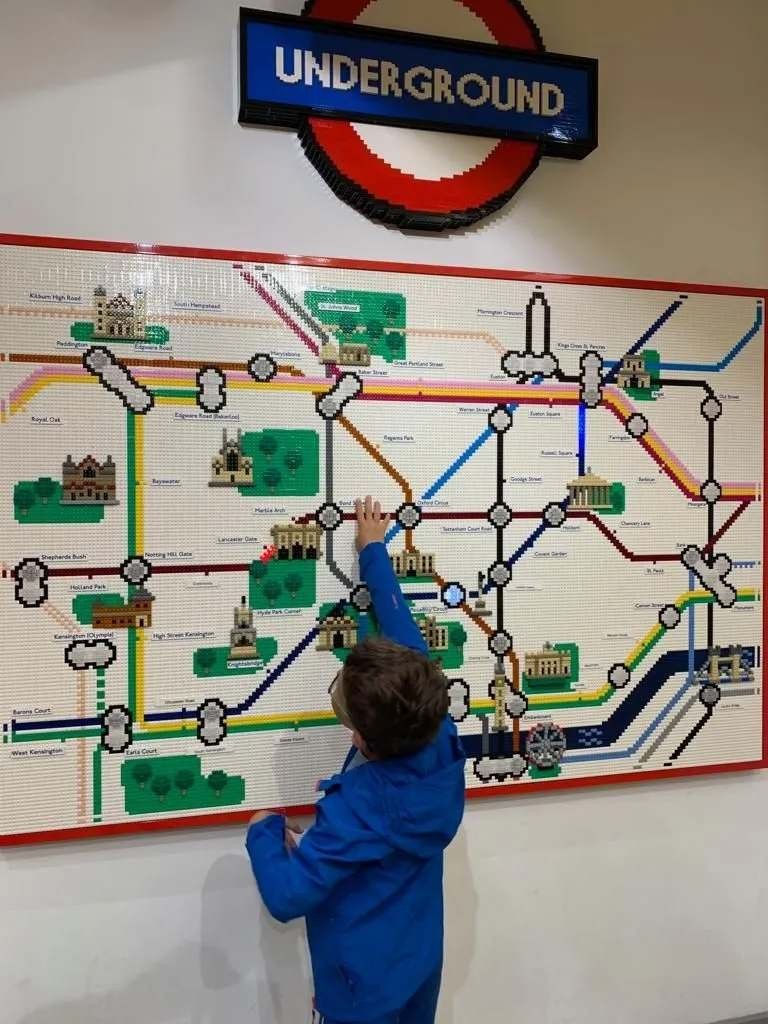 A kid playing with a Lego underground tube map.