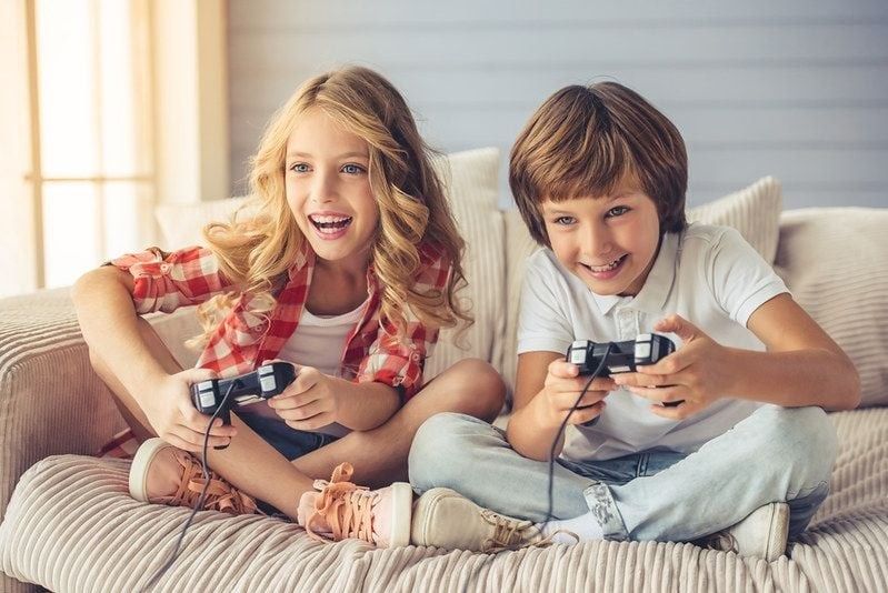Pretty little girl and boy are playing game console