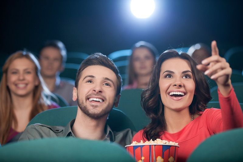 Cheerful young couple watching movie at the cinema