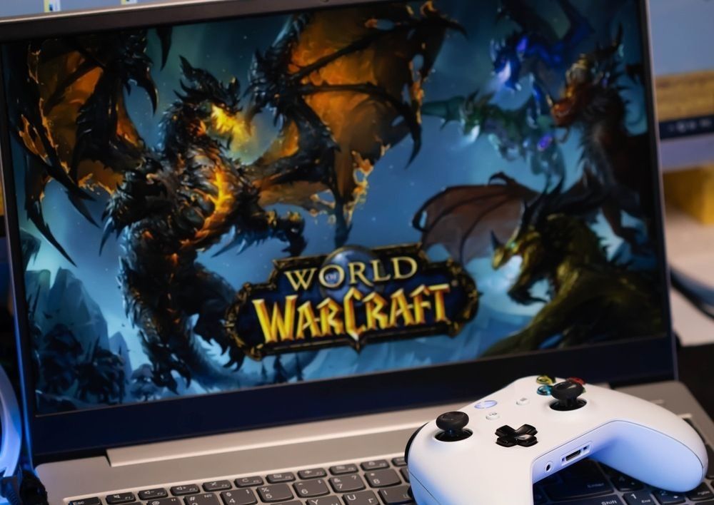 The game World of Warcraft is on the screen with a white Xbox game joystick.