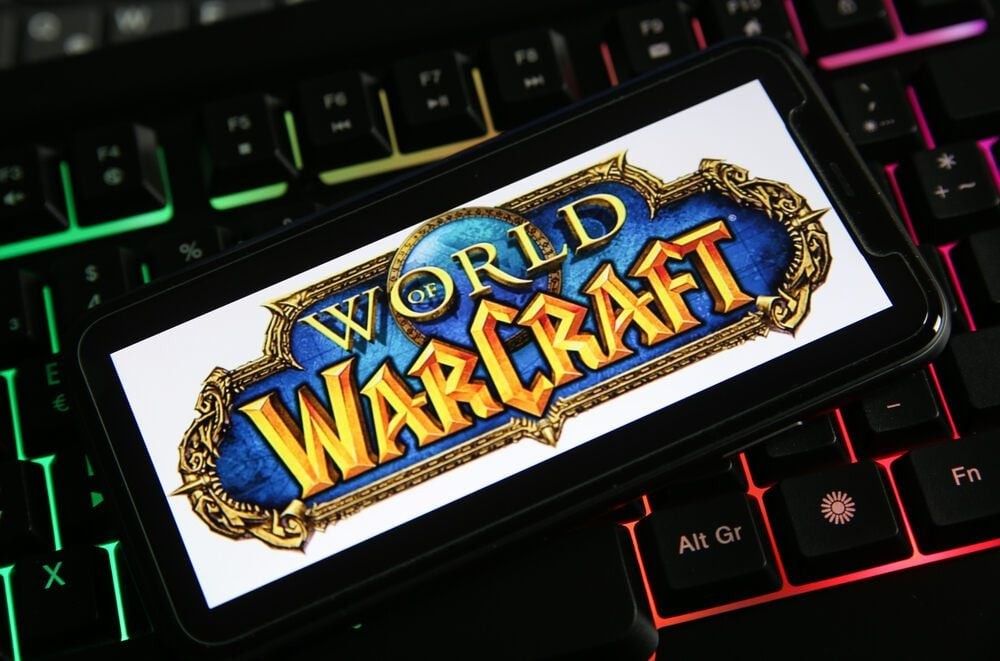Closeup of phone screen with logo of video game 'World of Warcraft' on computer keyboard